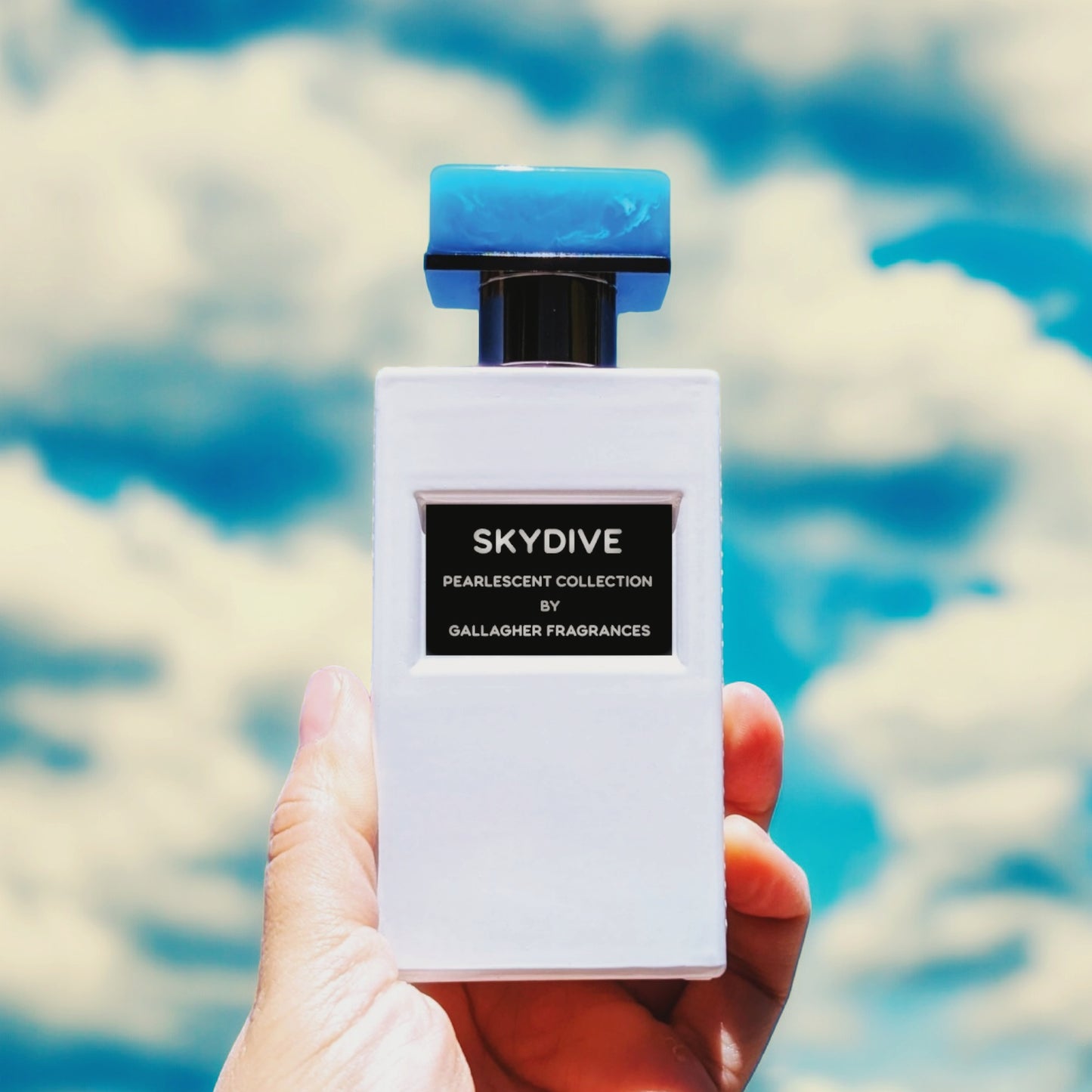 A bottle of SKYDIVE fragrance held against a sky with clouds.