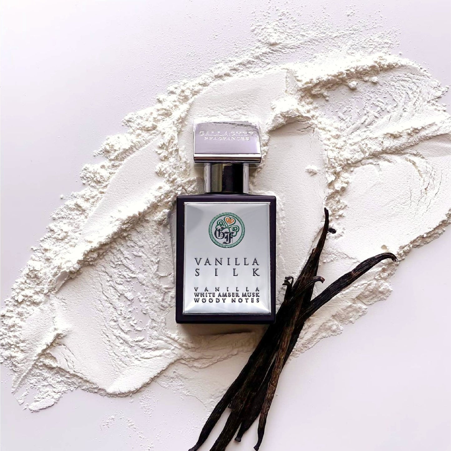 A bottle of Vanilla Silk perfume with a white label, accompanied by vanilla pods and white vanillin powder, presented on a white background.