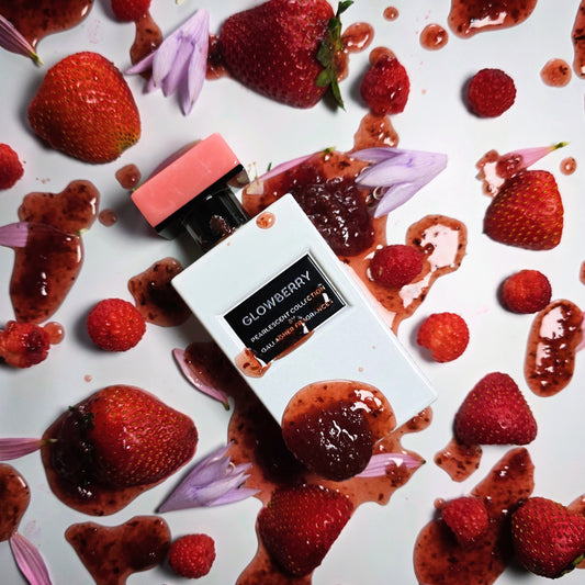 Perfume bottle labeled 'Glowberry' surrounded by strawberries and syrup on a light background